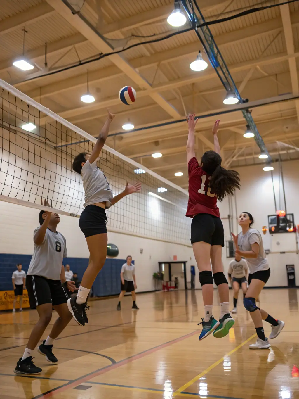 Students engaged in a volleyball match in the school gymnasium, demonstrating the ASSOCIATION SPORTIVE COLLEGE VOLTAIRE's volleyball program's emphasis on coordination and communication.
